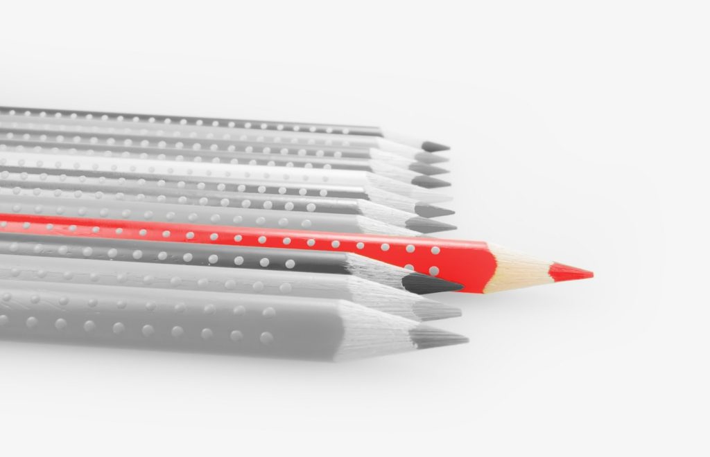 A row of grey pencils with a rogue red one.